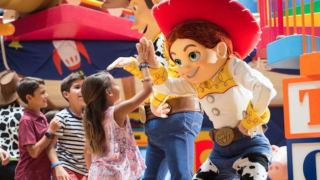 A group of smiling kids high five Woody and Jessie