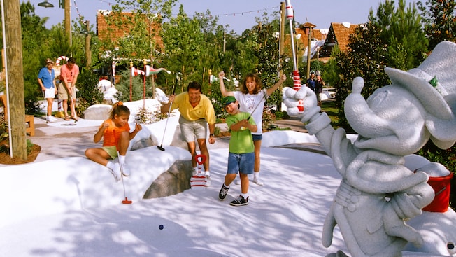 A boy swings his club on the faux snow at Disney's Winter Summerland Miniature Golf Course