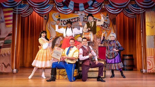 The cast of Hoop Dee Doo Musical Revue, 3 men and 3 women, pose on stage holding musical instruments.