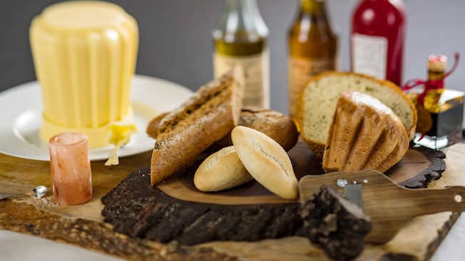 French baguette, brioche and multi grain bread served together on a wooden plate
