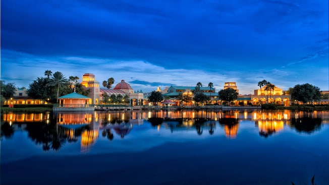A lake view of Disney's Coronado Springs Resort, lit up in the evening
