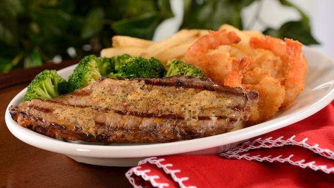 A grilled steak with a side of fried shrimp, French fries and broccoli
