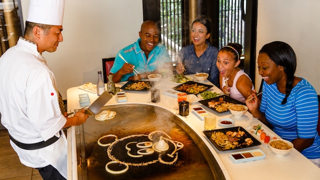 A Chef and 4 Guests marvel at his handiwork: a Mickey image made of onions on a grill