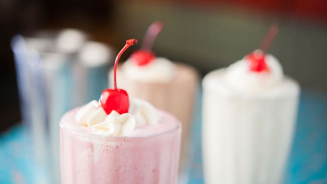 Strawberry, chocolate and vanilla shakes, each topped with whipped cream and a cherry 