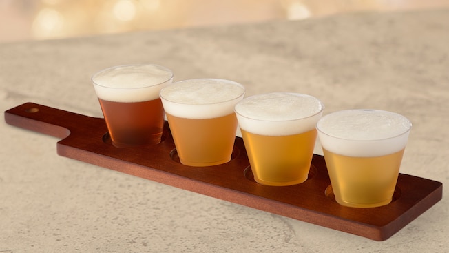 4 glasses of various beers rest on a paddle
