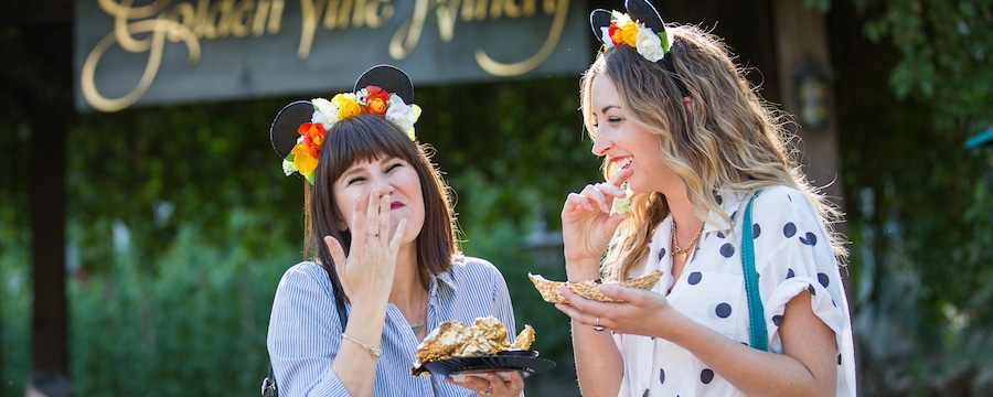 Two women laugh as they enjoy food from the Festival Marketplace