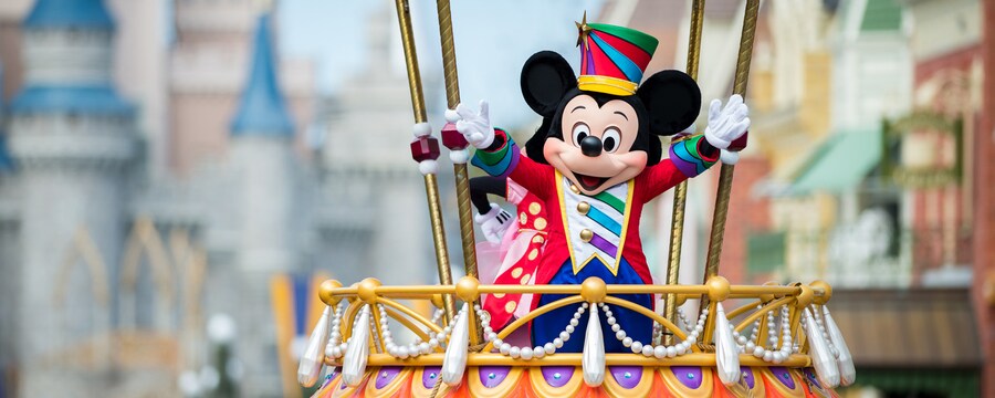 for dining packages at Walt Disney World: Mickey Mouse dressed in a festive costume waves excitedly during the Disney Festival of Fantasy Parade